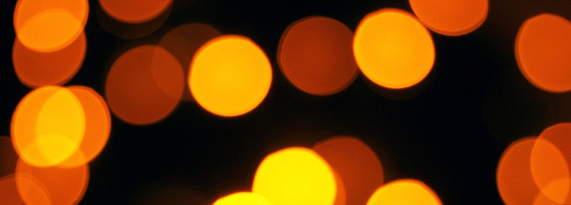 Gold-gelbe Punkte auf schwarzem Hintergrund, leicht verschwommen, wie Lichter, die in der nacht funkeln